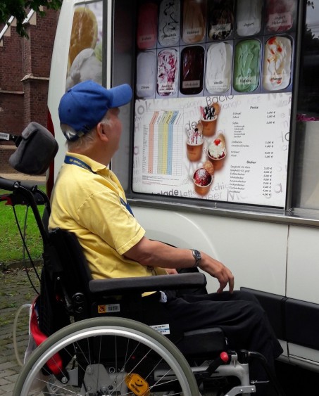Kunde im Rollstuhl sucht sich ein Eis an einem Eiswagen aus.