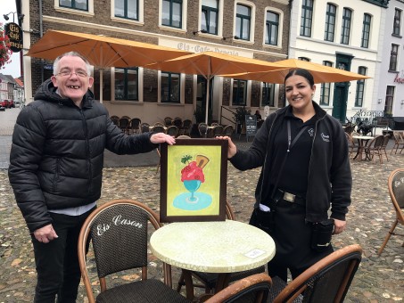 Michael Z. überreicht sein Kunstwerk Iljana G. vor dem Eis Café Venezia